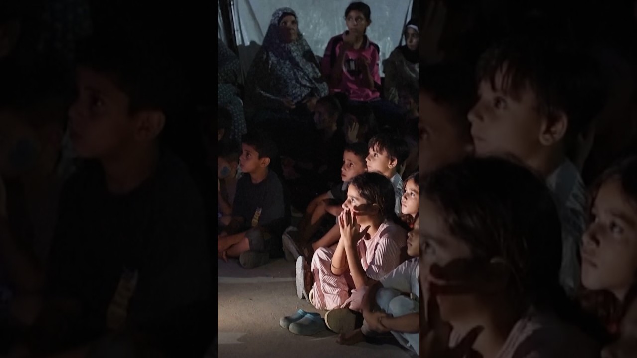 Children in Gaza gather between tents to watch cartoons
